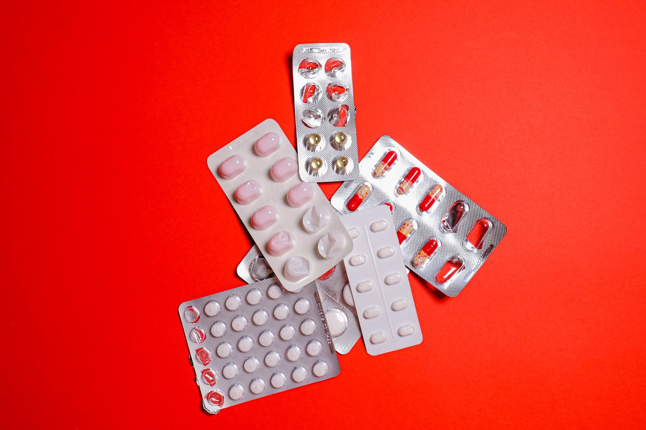 Blister packs with assorted pills over a vibrant red surface. Ideal for healthcare themes.